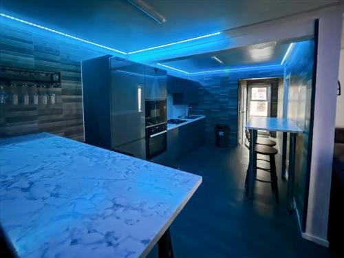 une cuisine avec un éclairage bleu et une table avec un tabouret dans l'établissement Cozy Hideaway With Hot Tub Sauna Sleeps 7, à Falmer