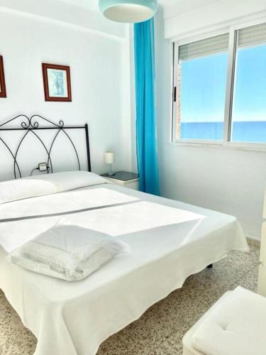 a white bedroom with a large bed with a window at APCOSTAS - Torre del Mar Playa - MALAGA in Torre del Mar