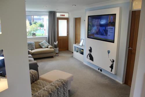 a living room with a couch and a flat screen tv at Beautiful home near beach in Formby