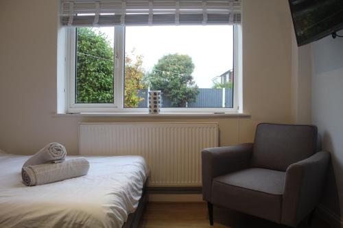Un dormitorio con una cama y una silla y una ventana. en Beautiful home near beach, en Formby