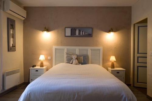 a bedroom with a white bed with a teddy bear on it at Le Crillon in Murs