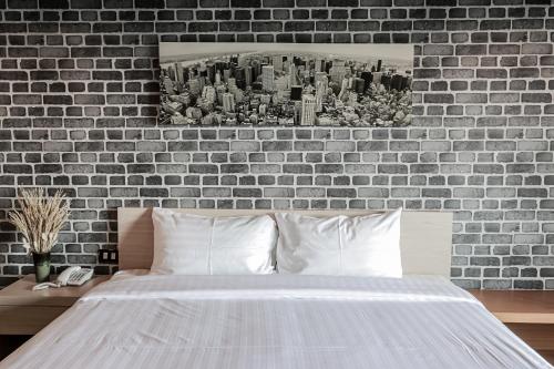 a bed in a bedroom with a brick wall at Get Zleep Premium Budget Hotel in Chiang Mai