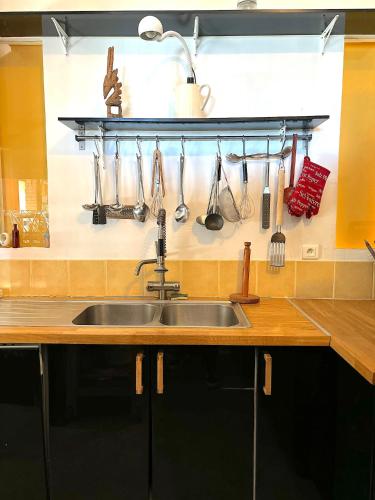 - un évier de cuisine avec des ustensiles accrochés au mur dans l'établissement Cottage Coeur des Vignes, à Fargues