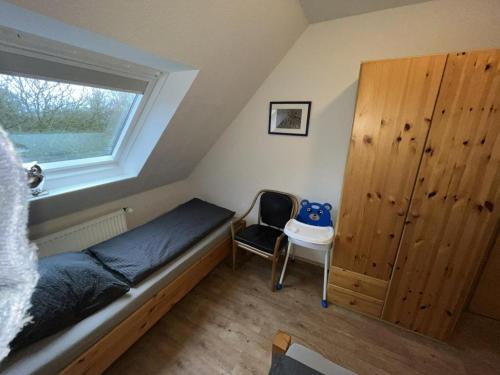 una camera da letto con un letto, una sedia e una finestra di !!!NEU!!! Ferienwohnung an der Harle OG a Carolinensiel