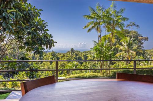 a table on a balcony with a view of the forest at House 15 Min From The Beach With River Access in Ojochal