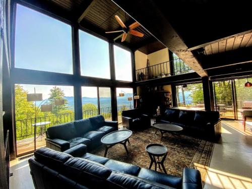 a living room with couches and tables and large windows at RL Breathtaking views and grand unique style private mountain retreat 4WD recommended in Whitefield