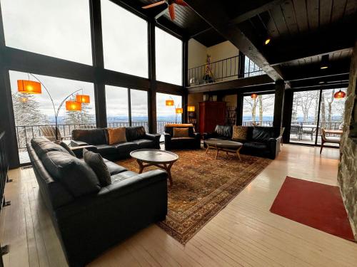 a living room with couches and tables and large windows at RL Breathtaking views and grand unique style private mountain retreat 4WD recommended in Whitefield