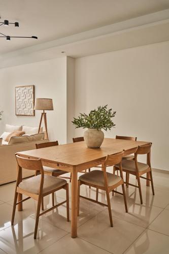a wooden table with chairs and a potted plant on it at Luxury Seaview 2BR - Paramount Midtown - 6 Guests - 64F Pool Access & Burj View in Dubai