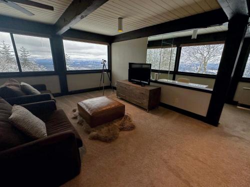 a living room with a couch and a tv and windows at RL Breathtaking views and grand unique style private mountain retreat 4WD recommended in Whitefield