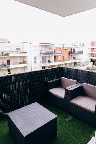 - un balcon avec 2 chaises, une table et des bâtiments dans l'établissement Appartement , Strasbourg France, à Strasbourg