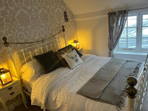 a bedroom with a bed with white sheets and a window at Corner Cottage in Knaresborough