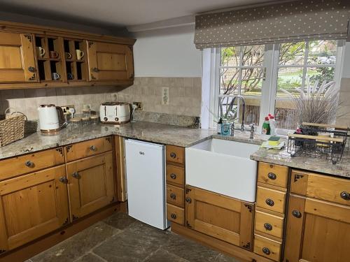 a kitchen with wooden cabinets and a white sink at Corner Cottage in Knaresborough