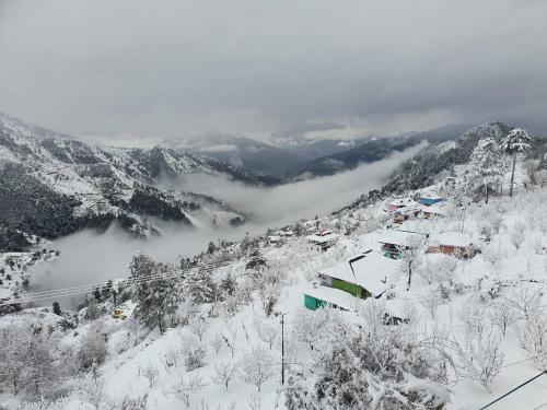 a snow covered mountain with a ski resort in the distance at Ashirwad Homestay near Kufri in Theog