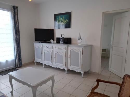 un salon avec une télévision et un meuble blanc dans l'établissement Les MOUSSES, à Varaville
