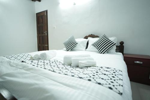 a white bed with black and white sheets and pillows at Wayanad Palm Grove Retreat 1st Floor in Wayanad