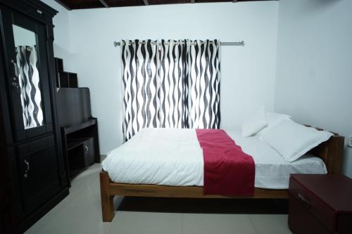 a bedroom with a bed with a red blanket and a window at Wayanad Palm Grove Retreat 1st Floor in Wayanad
