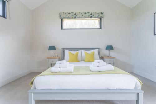 a white bedroom with a large bed with yellow pillows at Downs in Blewbury