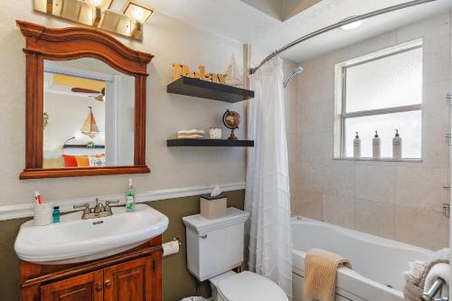 a bathroom with a sink and a toilet and a mirror at Wine-Dine-Sunshine Cozy Flat in The Heart of DTSP in St. Petersburg