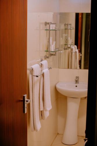 a bathroom with a sink and a toilet and towels at Corridor Springs Hotel in Arusha