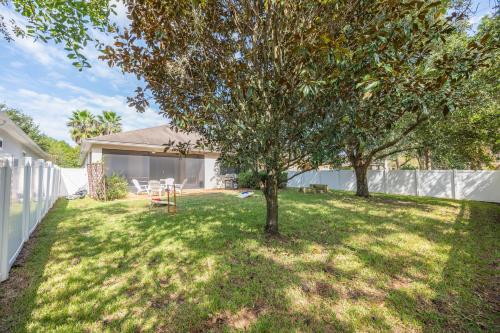 a yard with two trees and a fence at Nocatee Retreat with Fenced Yard & Lanai in Sampson