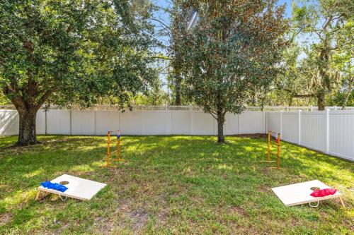 two playgrounds in a yard with trees and a fence at Nocatee Retreat with Fenced Yard & Lanai in Sampson