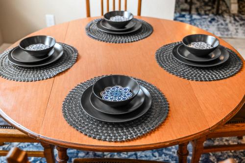 a wooden table with four black bowls and plates on it at Nocatee Retreat with Fenced Yard & Lanai in Sampson