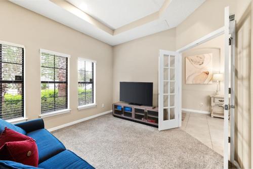 a living room with a blue couch and a tv at Nocatee Retreat with Fenced Yard & Lanai in Sampson
