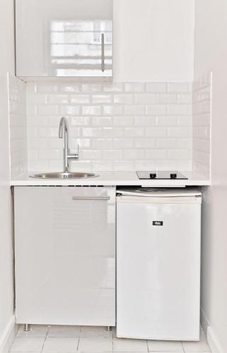 une cuisine blanche avec des armoires blanches et un évier dans l'établissement Magnifique appartement coloré #GareMontparnasse-II, à Paris