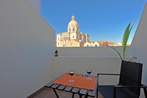 a table with two glasses of wine and a building at Alfama 2 - Attic with view in Lisbon