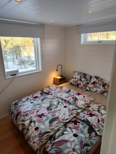 a bedroom with a bed with a floral comforter and a window at Magisch berghuisje met uitzicht op Nationaal Park Fulufjället in Sörsjön