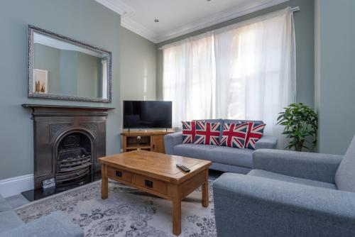 a living room with a couch and a table and a television at Lrg Stunning 5BD CrouchEnd House in London