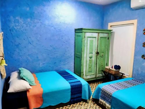 - une chambre bleue avec 2 lits et une armoire verte dans l'établissement México Lindo Cooking Boutique Valladolid, à Chichimilá
