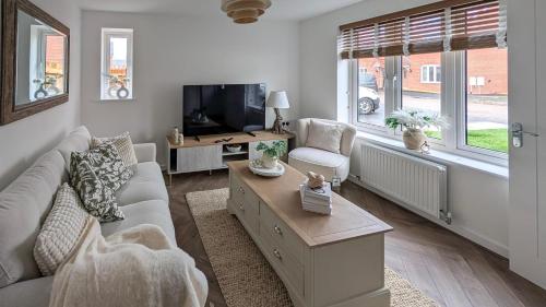 Una sala de estar con un sofá y un televisor. en Cotswold Green Sleeps 5 with Free ev Charge, en Tewkesbury