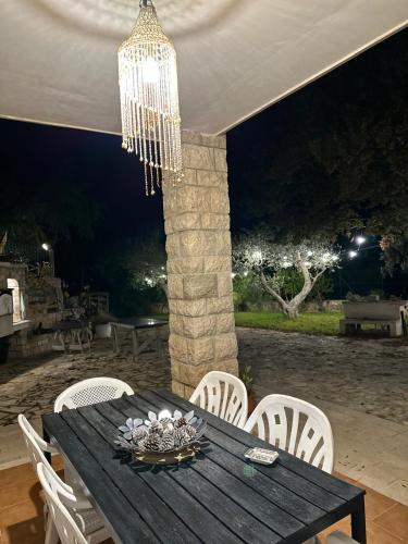 a dining table with white chairs and a chandelier at oasi di pace fasano BIS in Fasano