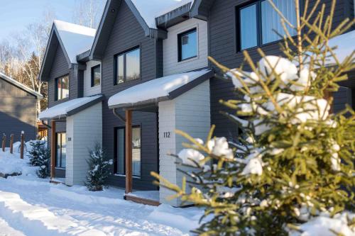 a black house with snow on the ground at Condos Kamik Tremblant by Manitonga in Mont-Tremblant
