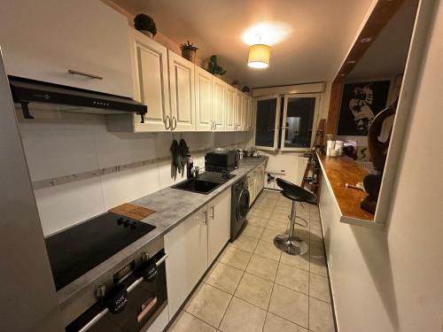 une cuisine avec des armoires blanches et un comptoir noir dans l'établissement Appartement Paris La Défense Metro L1/RER A, à Courbevoie