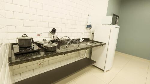a kitchen with two pots on a stove with a refrigerator at Jahu Center Plaza Flats in Jaú