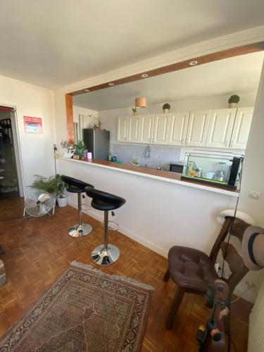 - une cuisine avec un bar et deux tabourets dans une pièce dans l'établissement Appartement Paris La Défense Metro L1/RER A, à Courbevoie