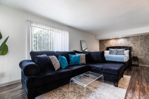 a living room with a black couch with blue pillows at MedCenter Apt Studio-NRG Prox in Houston