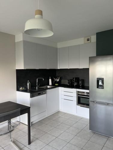 une cuisine avec des armoires blanches et un réfrigérateur en acier inoxydable dans l'établissement Les Côtes - Studio Dunes Du Golf - Vue mer - WMX, à Wimereux