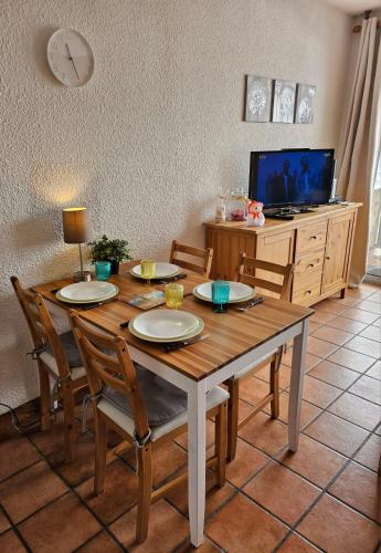 une table à manger avec quatre chaises et une télévision dans l'établissement le Meollion, à Orcières