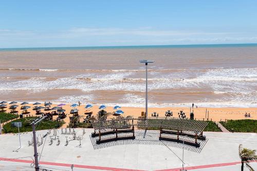a beach with benches and umbrellas and the ocean at INTER HOTEL JACARAÍPE in Serra