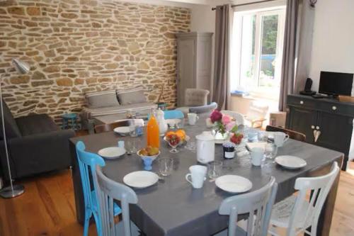 une table à manger avec des chaises et une table ainsi qu'une chambre avec un mur dans l'établissement Gîte Abord Paimpol, à Paimpol
