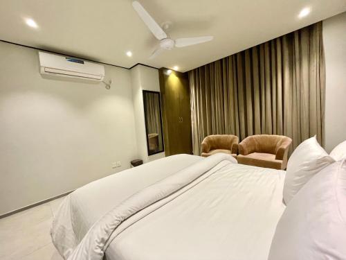 a bedroom with a large white bed and two chairs at Sense Luxury II - 2 bed Apartment in Islamabad