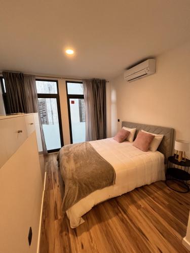 a bedroom with a large bed and some windows at Private 1 bedroom house in Machico Centre in Machico