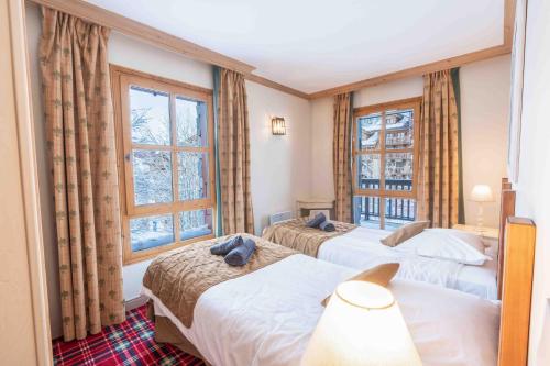 two beds in a room with two windows at Arc 1950 - 2 bed ski-in ski-out with stunning views in Arc 1950