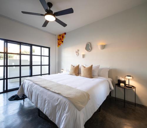 una camera da letto con un grande letto bianco e un ventilatore a soffitto di Casa Lumos - Minimalist Comfort Suites in Centro Historico a Città di Oaxaca