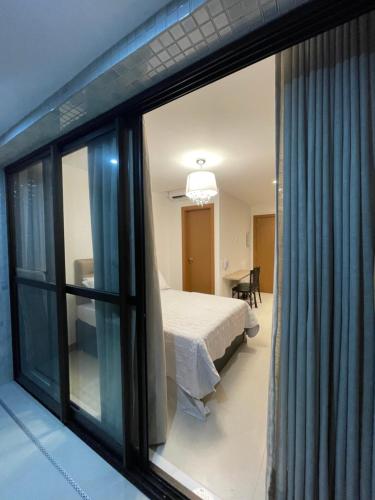 a bedroom with a bed and a large window at Novíssimo Studio na Barra a 500 metros da praia in Salvador