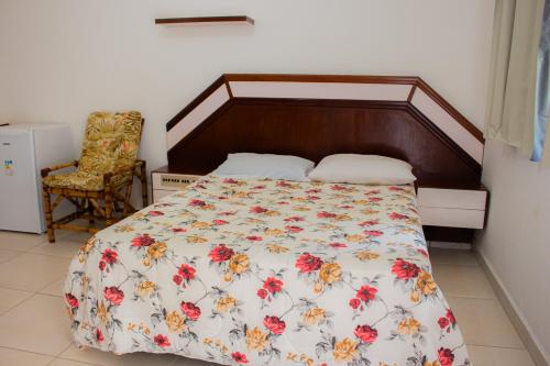 a bedroom with a bed with a floral bedspread at Hotel Fazenda Pé da Serra in Bom Sucesso