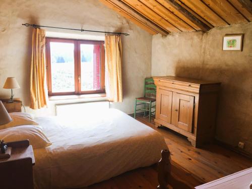 une chambre avec un grand lit et une fenêtre dans l'établissement Gîte La Petite Grange - En pleine nature ressourcement et randonnée, à La Pesse